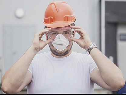 строитель в респираторе и очках за работой