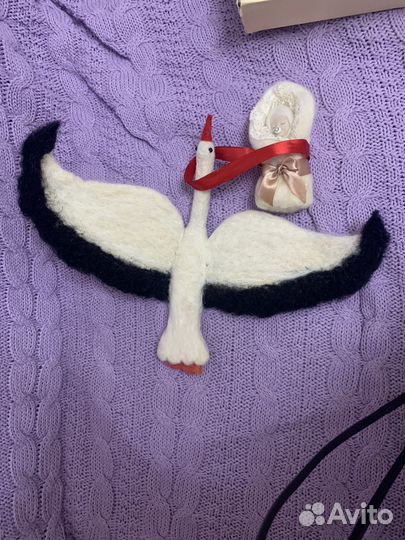 Аист с младенцем на красной ленте